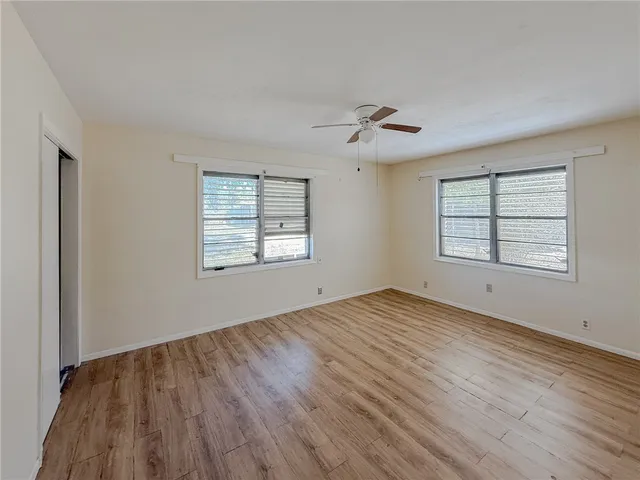 a view of empty room with wooden floor and fan