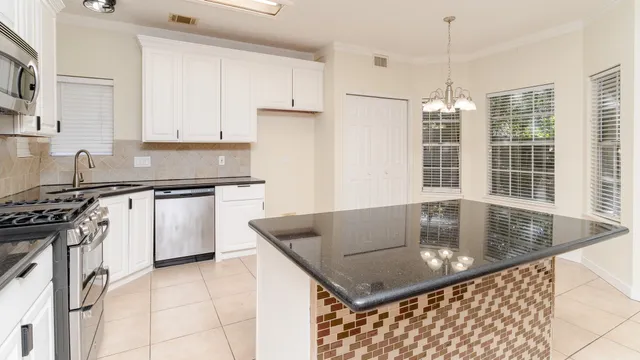 a kitchen with stainless steel appliances granite countertop a sink a stove top oven a counter space and cabinets