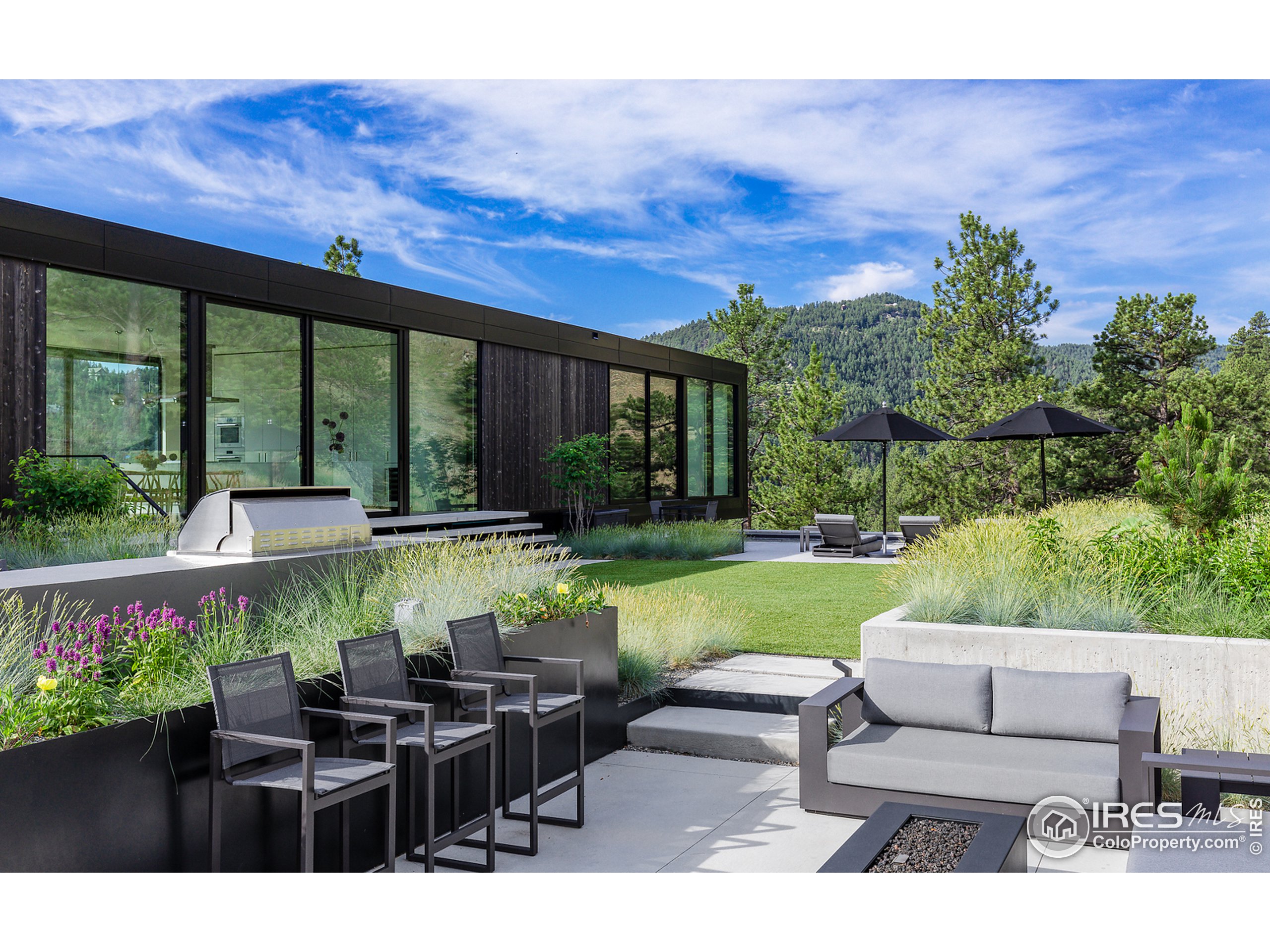 Undisclosed Address Boulder, CO 80302 - Photo 7 of 40 a view of a patio with couches table and chairs under an umbrella with a large tree