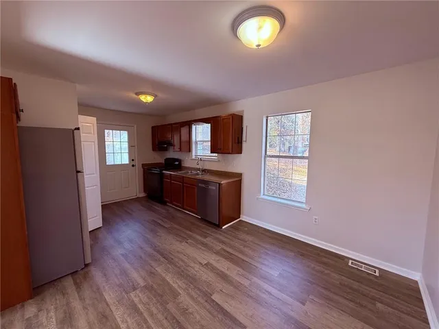 a kitchen with stainless steel appliances granite countertop a stove a sink dishwasher a refrigerator and a microwave oven with wooden floor