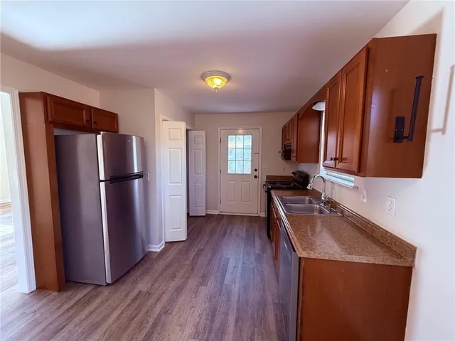 a kitchen with a refrigerator a sink and wooden floor