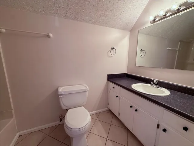 a bathroom with a granite countertop toilet sink and mirror
