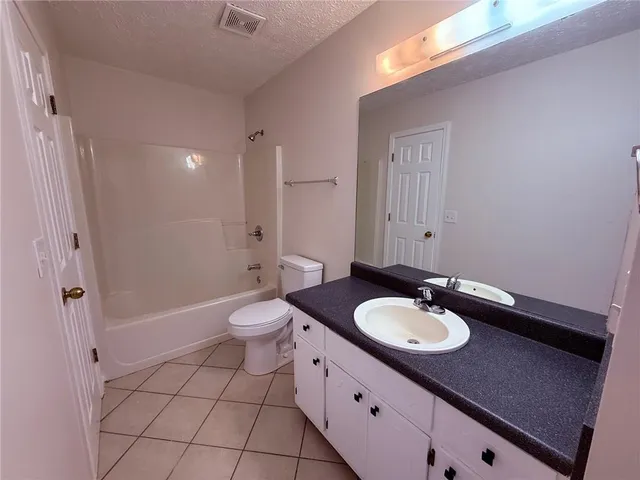a bathroom with a granite countertop sink toilet a mirror and shower