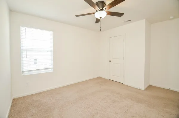 an empty room with a window and a fan