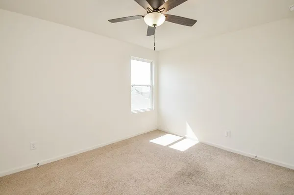 an empty room with a window and a fan