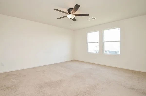 an empty room with ceiling fan and windows