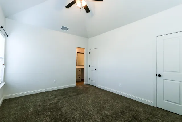 an empty room with ceiling fan and window