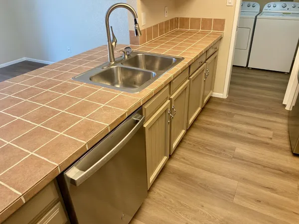 a close view of a sink and dishwasher with wooden floor