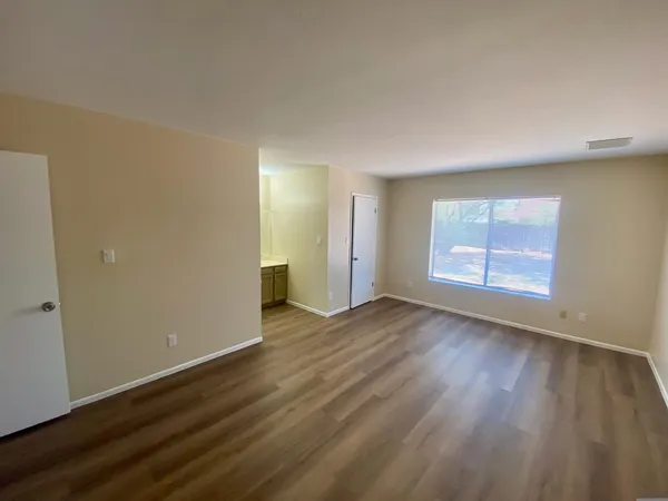 an empty room with wooden floor and windows