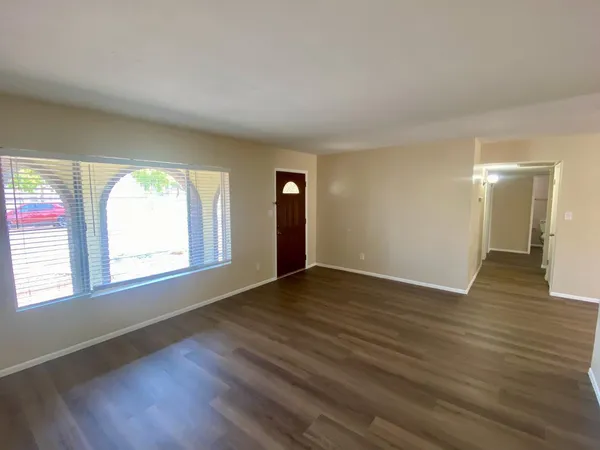an empty room with wooden floor and windows
