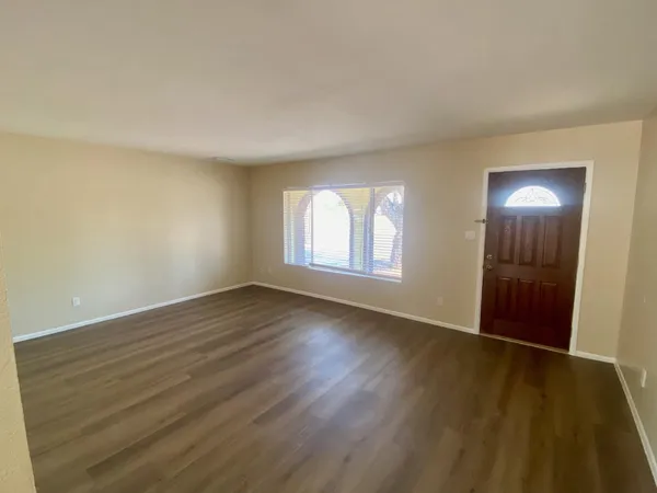 an empty room with wooden floor and windows