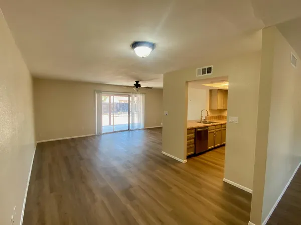 a view of a hallway with wooden floor and a bathroom