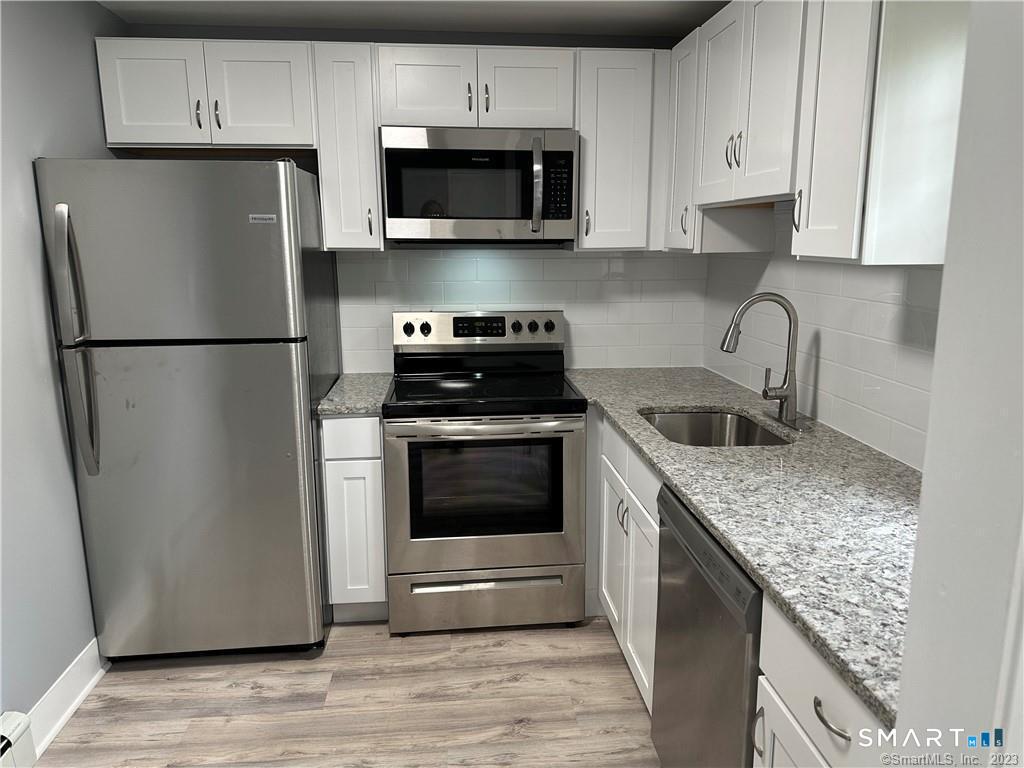 12 Brewster Road, Unit C Glastonbury, CT 06033 - Photo 3 of 10 a kitchen with refrigerator a microwave and cabinets
