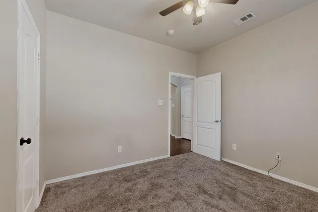 an empty room with a ceiling fan and entryway