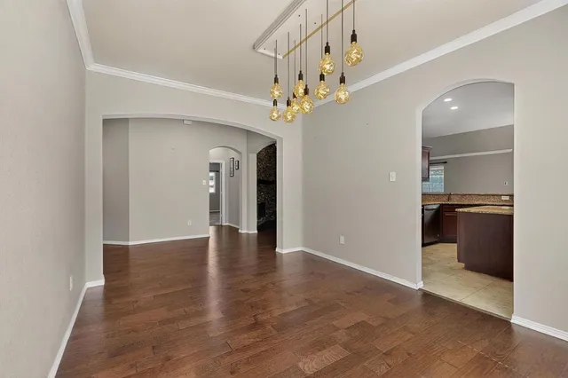wooden floor in an empty room with a chandelier fan