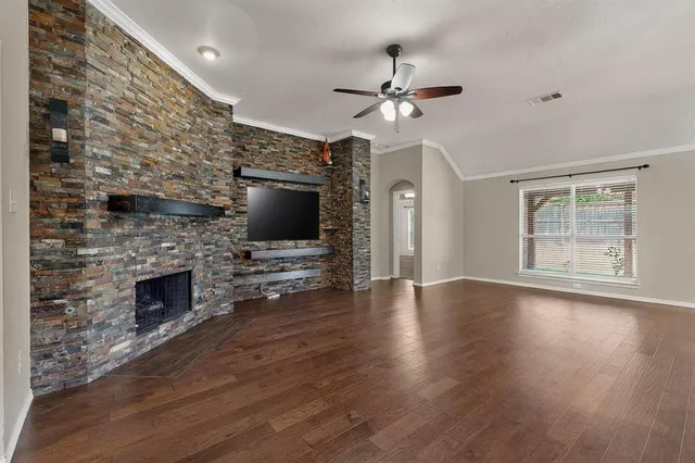 a view of an empty room with wooden floor fireplace and a window