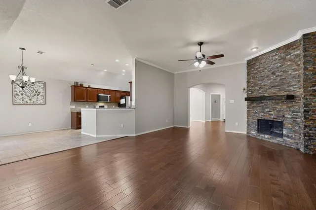 an empty room with wooden floor a kitchen view and a fireplace