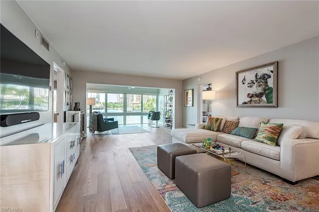 a living room with furniture large windows and wooden floor