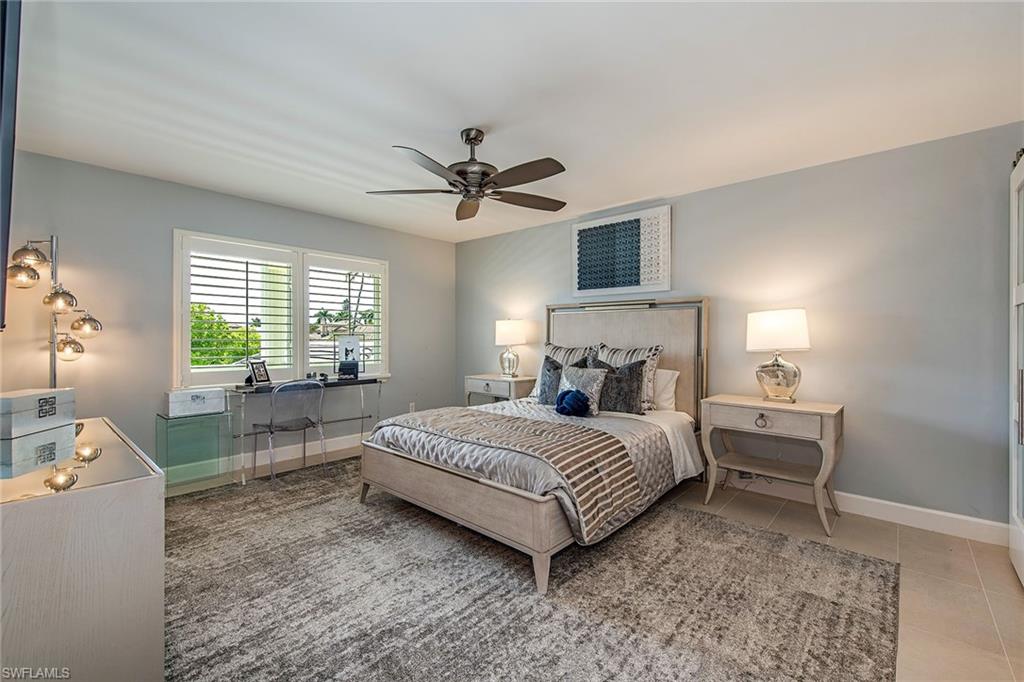 4155 Crayton Road, Unit 203 Naples, FL 34103 - Photo 6 of 12 a bedroom with a bed and a chandelier