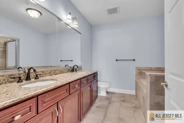 a bathroom with a granite countertop sink a toilet and a mirror