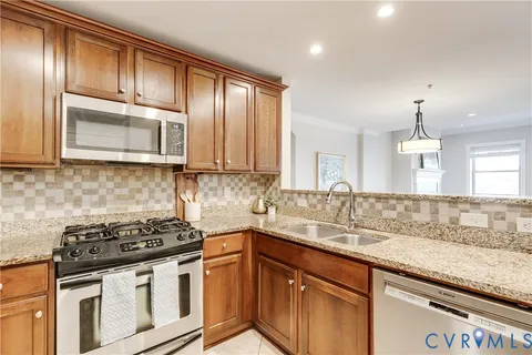a kitchen with stainless steel appliances granite countertop a stove a sink and a microwave