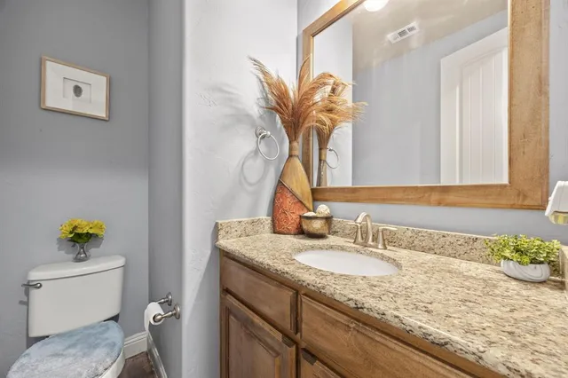 a bathroom with a granite countertop sink a toilet and a mirror