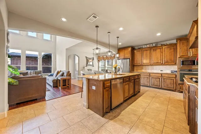 a kitchen with stainless steel appliances granite countertop a stove top oven a sink dishwasher a dining table and chairs