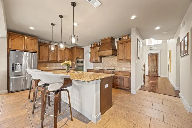 a kitchen with stainless steel appliances kitchen island granite countertop a refrigerator and a sink