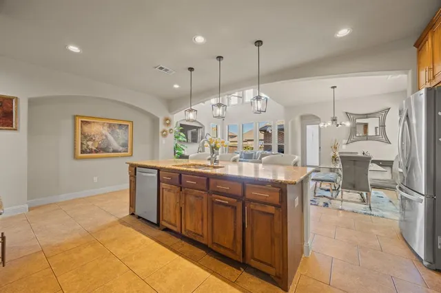 a large kitchen with kitchen island a stove a sink a counter space and a chandelier