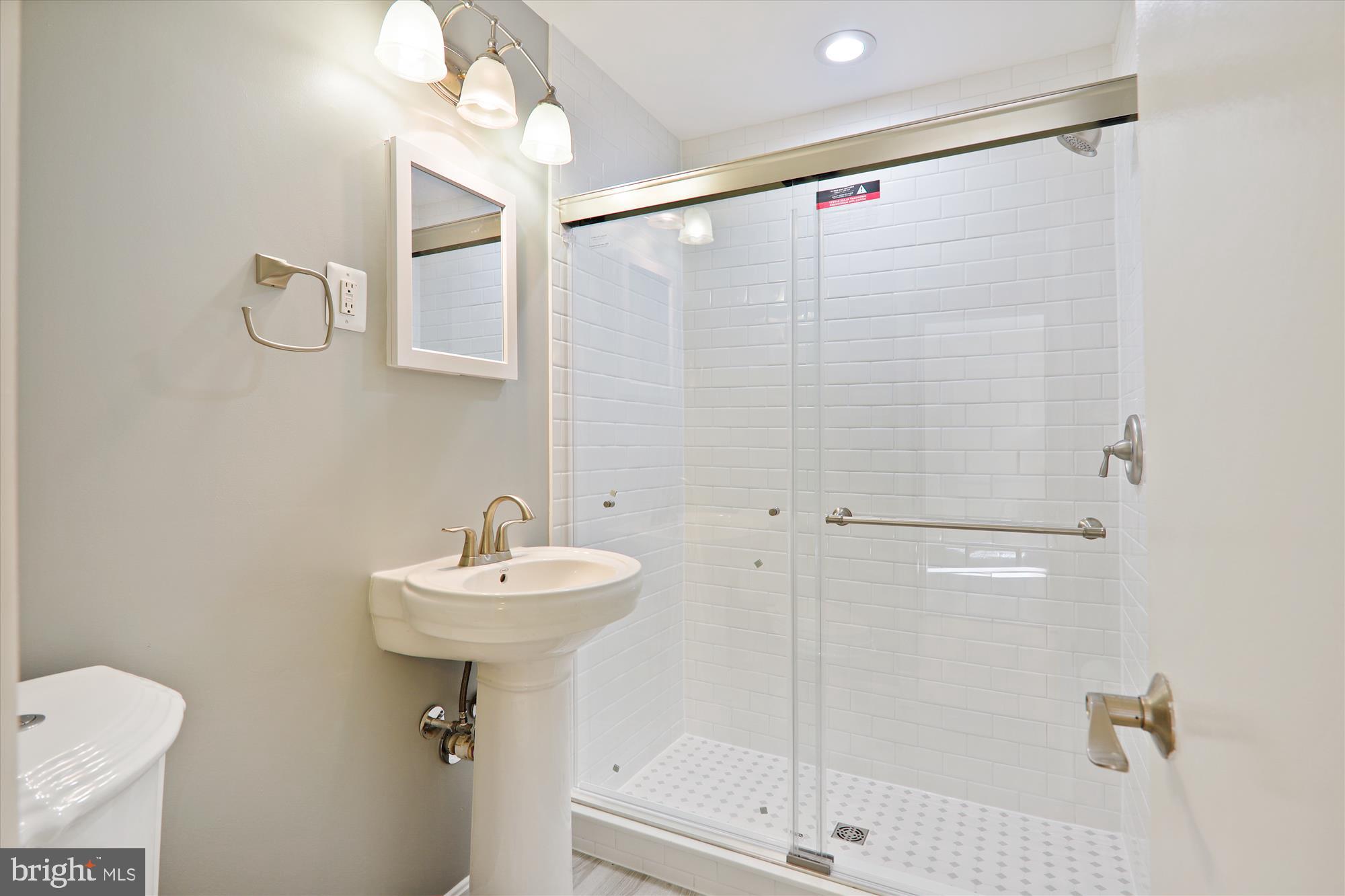 4970 Battery Lane, Unit 408 Bethesda, MD 20814 - Photo 18 of 40 a bathroom with a sink mirror and a shower