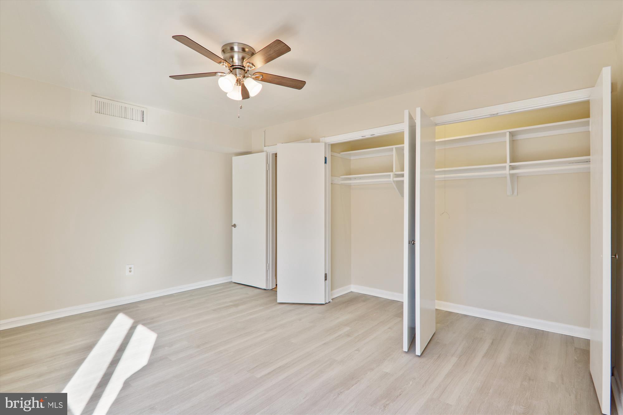 4970 Battery Lane, Unit 408 Bethesda, MD 20814 - Photo 21 of 40 a view of an empty room with wooden floor and a ceiling fan