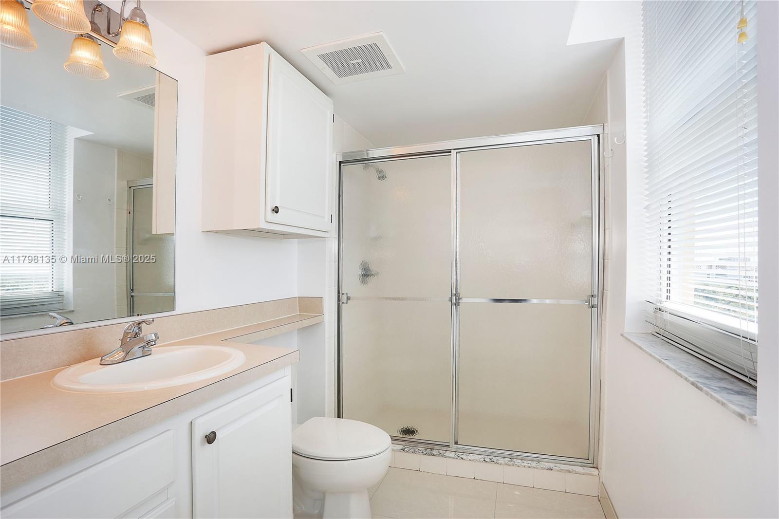 2665 Southwest 37th Avenue, Unit 1506 Miami, FL 33133 - Photo 5 of 19 a bathroom with a shower sink vanity mirror and toilet