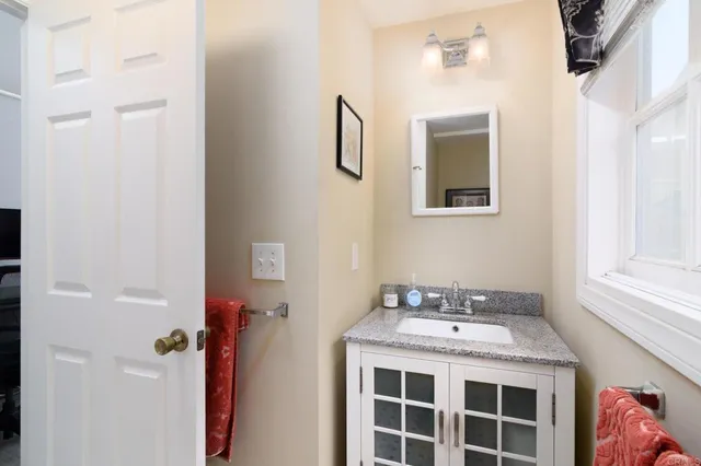a bathroom with a granite countertop sink a mirror and shower