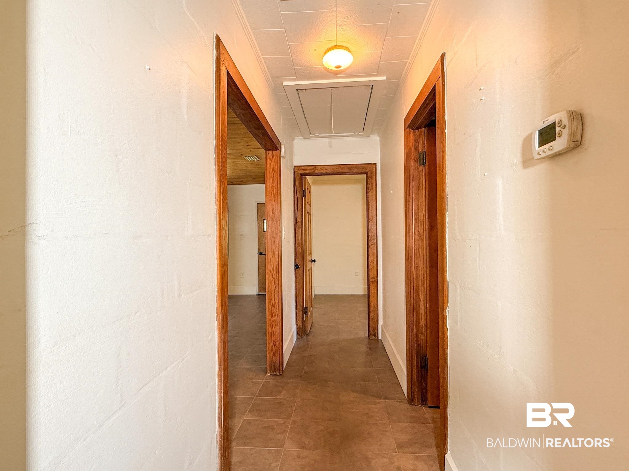 18711 Keller Road Foley, AL 36535 - Photo 18 of 38 Hallway featuring wood-finish door frames, tile flooring, and a ceiling-mounted light fixture