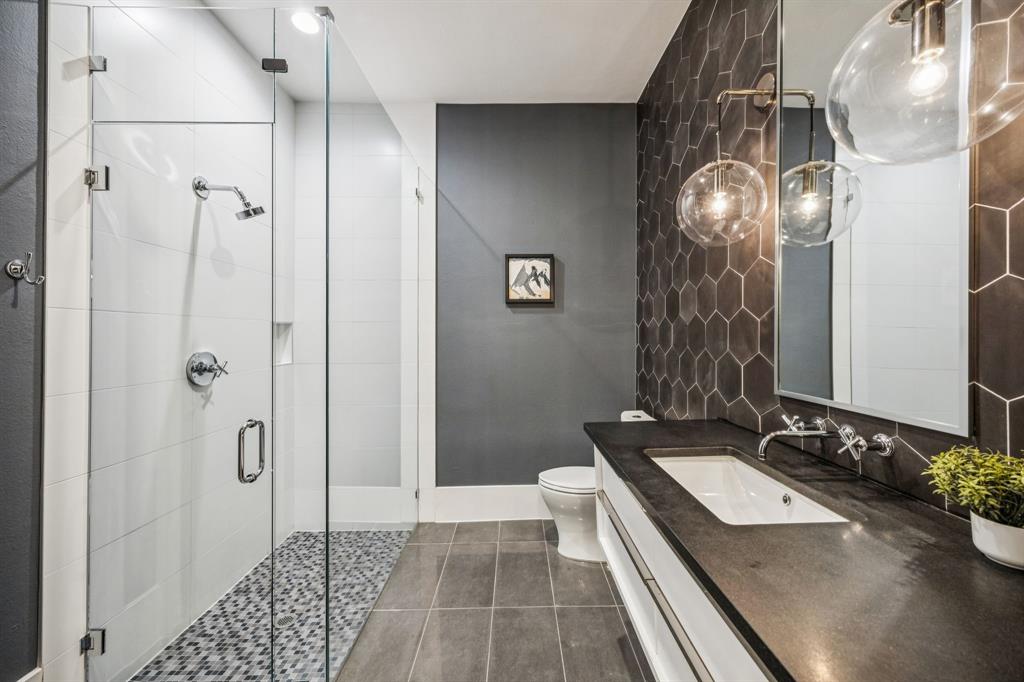 4330 Ridge Road Dallas, TX 75229 - Photo 19 of 30 a bathroom with a granite countertop sink a toilet a mirror and shower