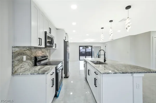 a kitchen with stainless steel appliances granite countertop a sink a stove and a refrigerator