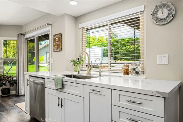 a large kitchen with stainless steel appliances a stove a sink dishwasher a refrigerator white cabinets and wooden floor
