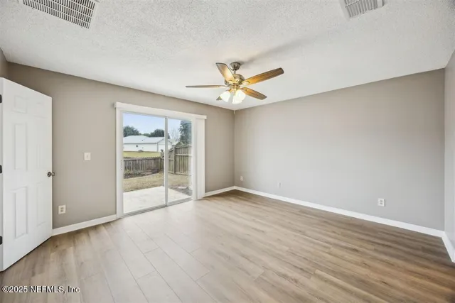 an empty room with wooden floor and ceiling fan