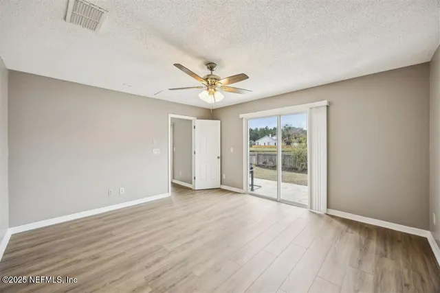 an empty room with wooden floor and ceiling fan