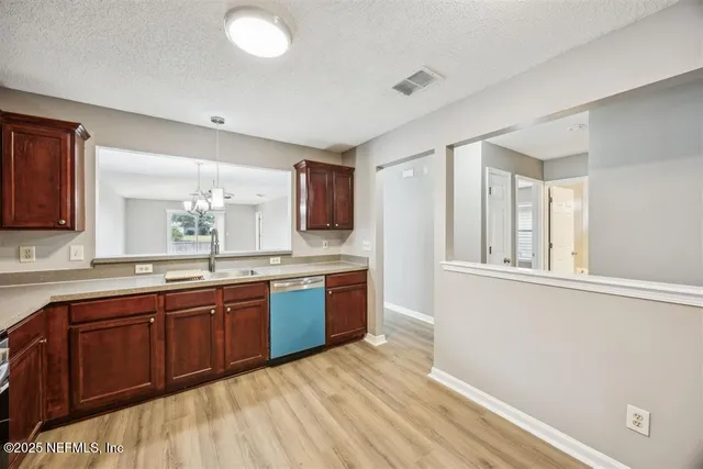 a large kitchen with stainless steel appliances granite countertop a sink dishwasher stove and wooden cabinets