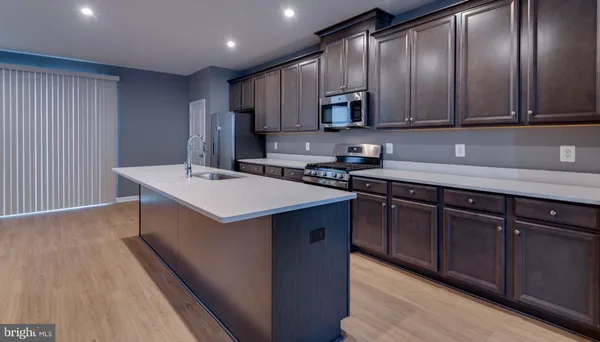 a kitchen with stainless steel appliances granite countertop a stove a refrigerator and a sink with wooden cabinets