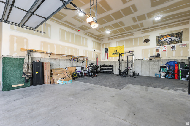 2056 West Ridgeline Road Stockton, UT 84071 - Photo 34 of 50 Spacious garage featuring a concrete floor, exposed drywall with taped seams, and a partially open overhead garage door