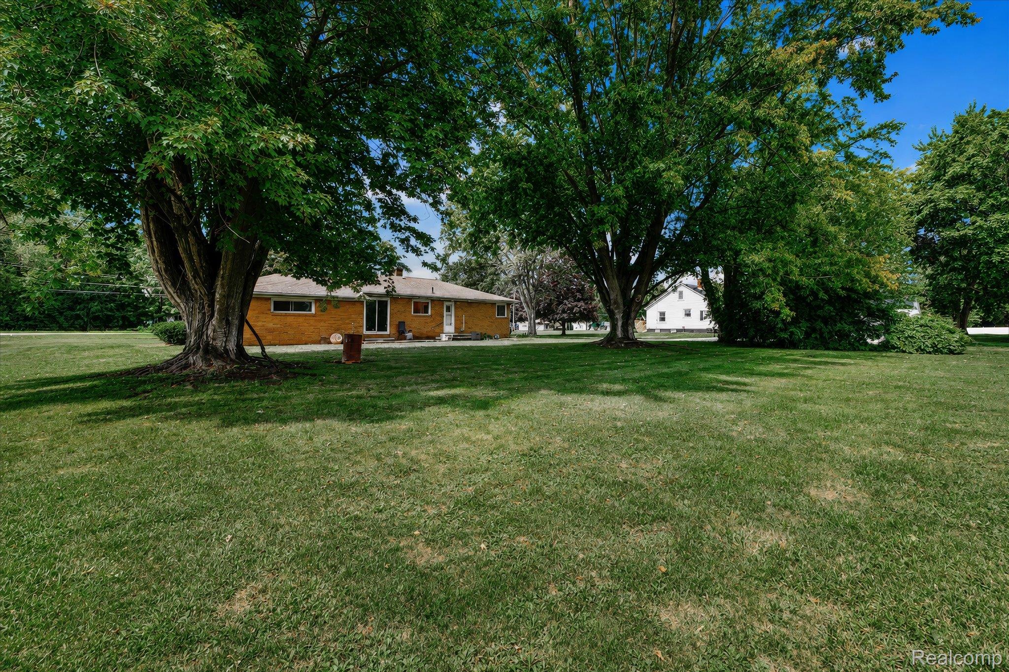 4499 South Linden Road Flint, MI 48507 - Photo 28 of 32 Expansive green lawn with mature trees and a single-story brick exterior