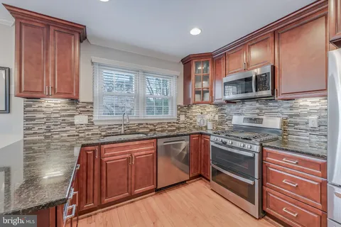 a kitchen with granite countertop a stove microwave and refrigerator