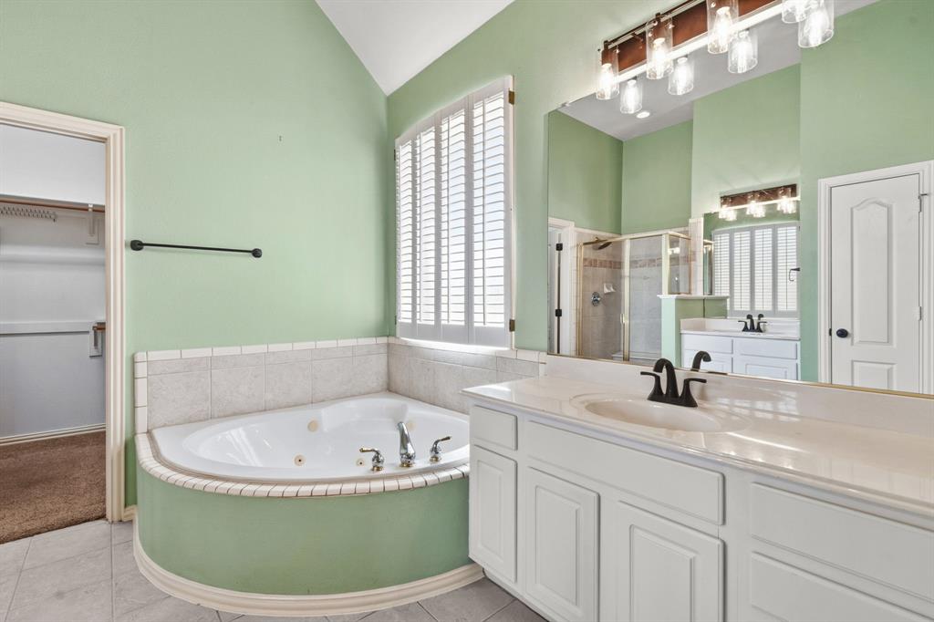 7517 Rodeo Drive Denton, TX 76208 - Photo 24 of 39 The primary bathroom features a jetted tub, separate vanities, and a large walk-in closet.