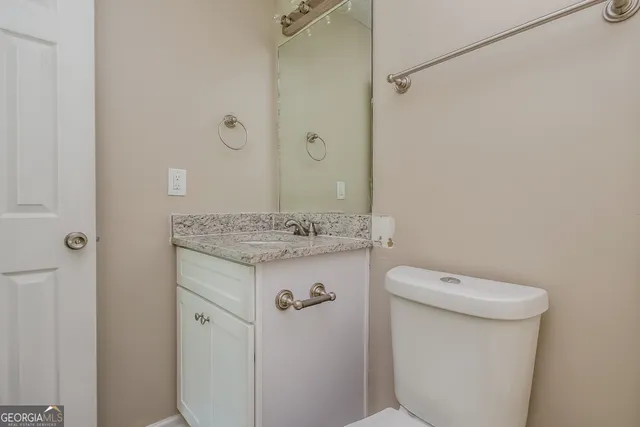 a bathroom with a granite countertop toilet a sink and a mirror