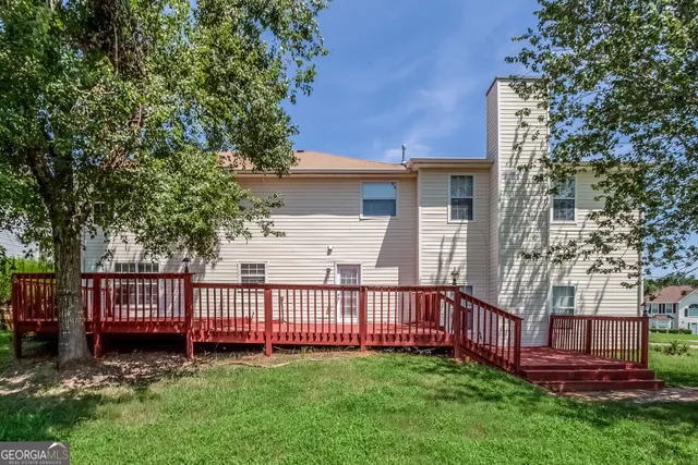 a view of a wooden house with a small yard and a large tree