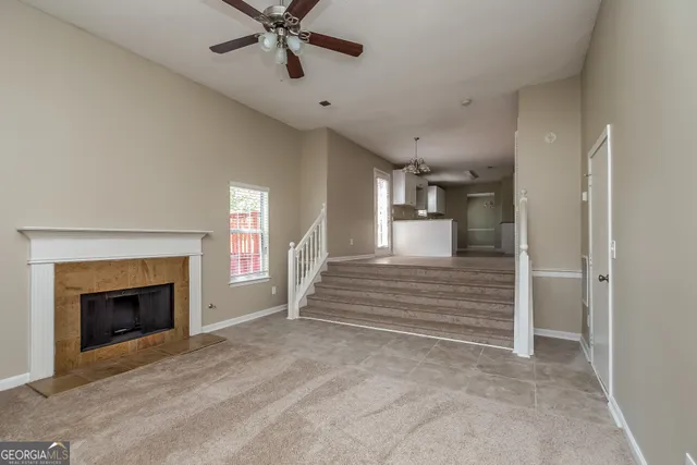 a view of a livingroom with a fireplace a ceiling fan and windows