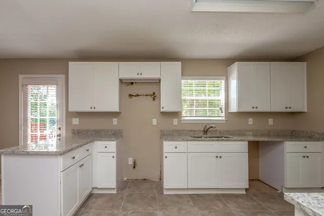 a kitchen with white cabinets appliances a sink and a window