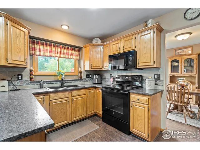 a kitchen with stainless steel appliances granite countertop a stove top oven a sink dishwasher a dining table and chairs with wooden floor